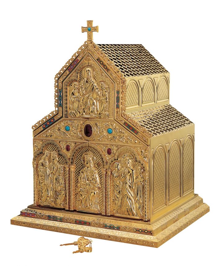 tabernacolo da mensa romanico in ottone dorato, proponente una chiesa ricca di decorazioni sul fronte e impreziosita da pietre colorate incastonate